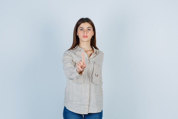 Retrato de jovencita mostrando espera en un gesto de un minuto en casual, jeans y mirando confiada vista frontal