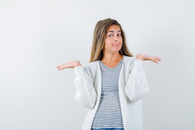 Retrato de jovencita mostrando gesto de bienvenida en camiseta, chaqueta y mirando confiado vista frontal