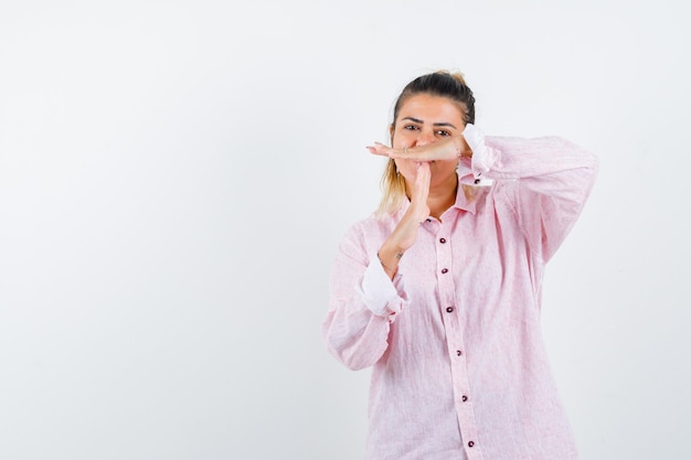 Retrato de jovencita mostrando gesto de descanso en camisa rosa y mirando feliz vista frontal