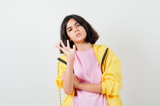 Retrato de jovencita mostrando gesto de parada en camiseta, chaqueta y mirando irritada vista frontal