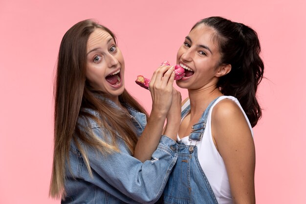 Retrato de jóvenes adolescentes posando juntos y comiendo donas