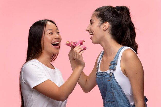 Retrato de jóvenes adolescentes posando juntos y comiendo donas