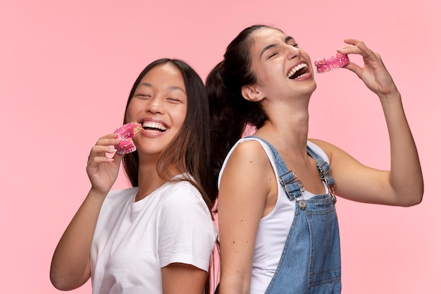 Retrato de jóvenes adolescentes posando juntos y comiendo donas