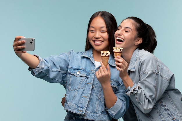 Retrato de jóvenes adolescentes tomando un selfie mientras sostiene helados