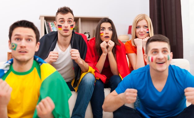Retrato de jóvenes aficionados al fútbol durante la visualización del partido en la televisión
