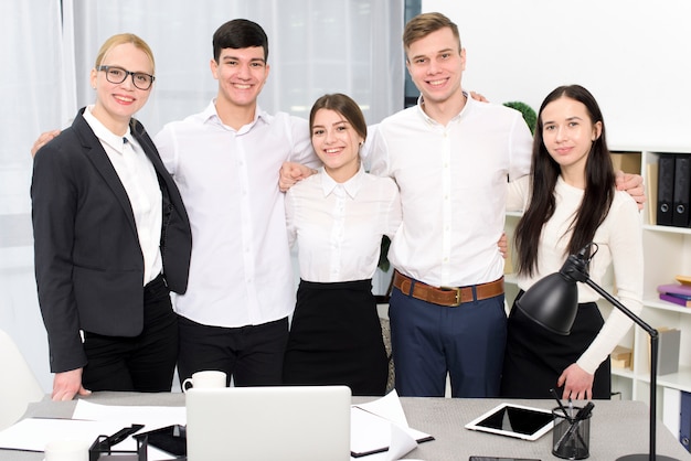 Retrato de jóvenes empresarios con sus brazos alrededor de los hombros en la oficina