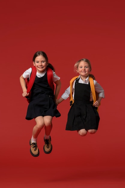 Foto gratuita retrato de jóvenes estudiantes en uniforme escolar saltando en el aire