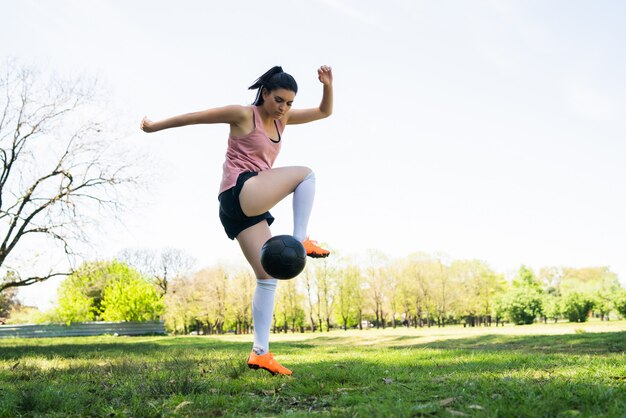 Retrato del jugador de fútbol femenino joven que entrena y que practica habilidades en campo de fútbol. Concepto deportivo