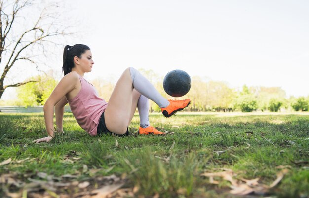 Retrato del jugador de fútbol femenino joven que entrena y que practica habilidades en campo de fútbol. Concepto deportivo