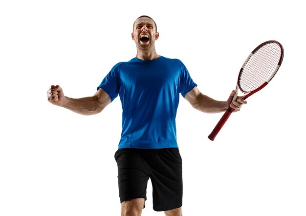 Retrato de un jugador de tenis masculino guapo celebrando su éxito aislado en una pared blanca. Las emociones humanas, ganador, deporte, concepto de victoria