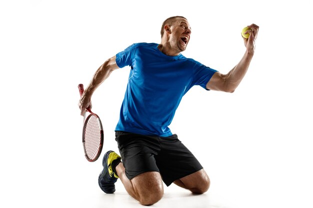 Retrato de un jugador de tenis masculino guapo celebrando su éxito aislado en una pared blanca. Las emociones humanas, ganador, deporte, concepto de victoria