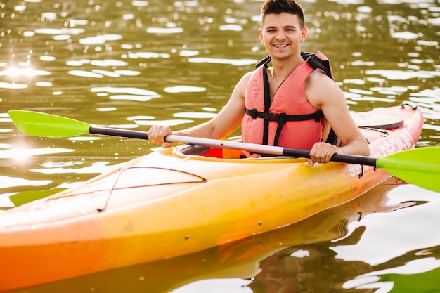 Retrato de kayakista masculino en la superficie de agua ondulada brillante