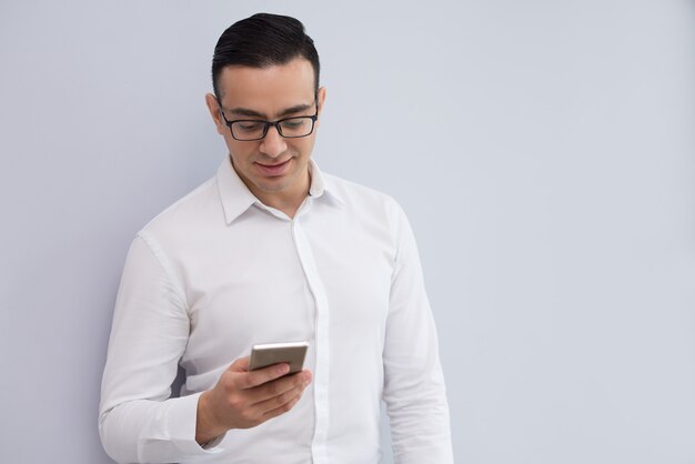 Retrato de la lectura feliz del hombre de negocios joven o del mensaje que manda un SMS