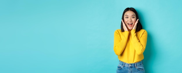 Foto gratuita retrato de una linda chica coreana recibe noticias sorprendentes que se ven asombradas y felices ante la cámara de pie o