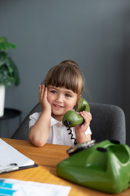 Retrato de linda chica hablando por teléfono rotatorio en la oficina