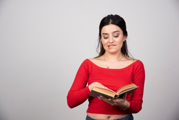 Retrato de linda joven estudiante morena mirando un libro abierto.