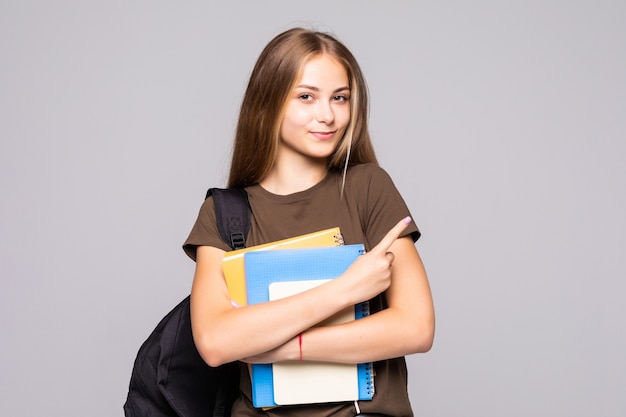 Retrato de linda joven estudiante morena sosteniendo cuadernos aislados en la pared blanca