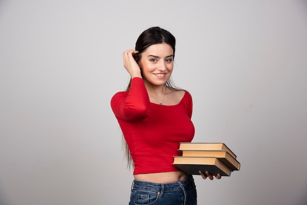 Foto gratuita retrato de linda joven estudiante morena sosteniendo libros.