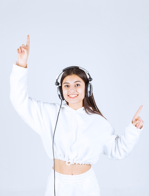 Retrato de una linda joven modelo de pie con auriculares.