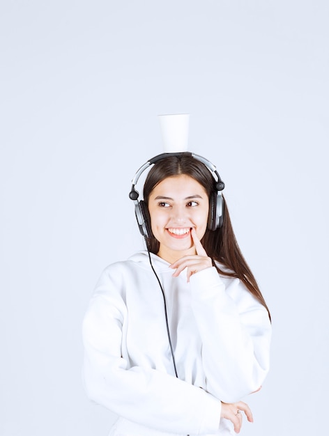 Retrato de una linda joven modelo de pie con auriculares.