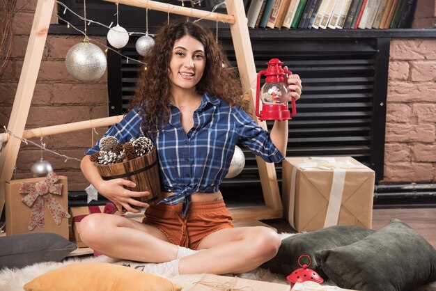 Retrato de una linda joven sosteniendo una canasta de madera de piñas