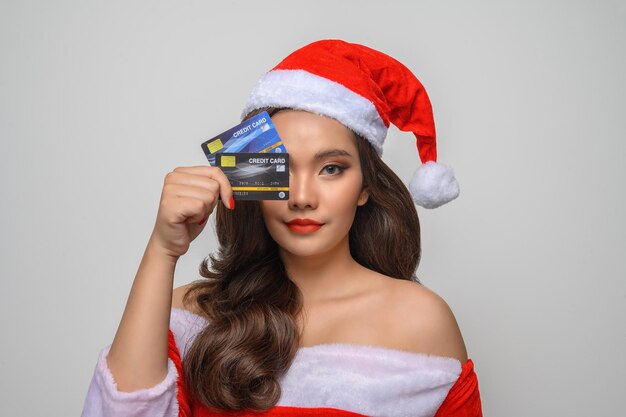 Retrato de linda mujer asiática en traje de Santa posando con tarjeta de crédito en la mano