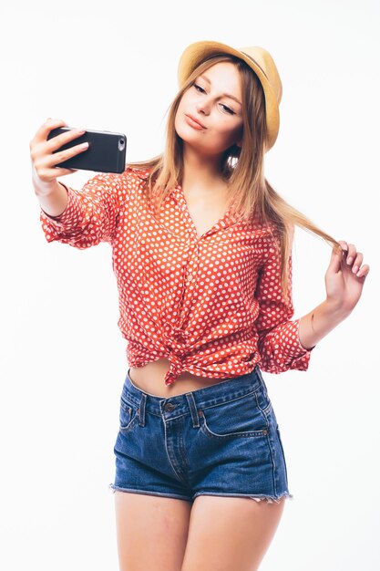 Retrato de una linda mujer sonriente haciendo foto selfie en smartphone aislado sobre un fondo blanco.