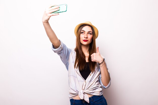 Retrato de una linda mujer sonriente haciendo foto selfie en smartphone en un blanco