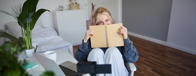 Foto gratuita retrato de una linda y sonriente joven creadora de contenido de redes sociales que graba video en una cámara digital y