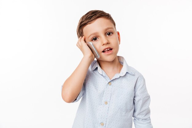 Foto gratuita retrato de un lindo niño pequeño hablando por teléfono móvil