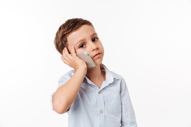 Retrato de un lindo niño pequeño hablando por teléfono móvil