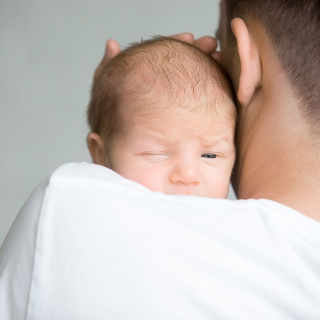Retrato de un lindo recién nacido asimiento en el hombro del padre