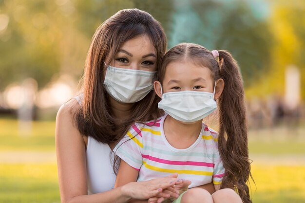 Retrato de madre e hija asiáticas con máscaras médicas