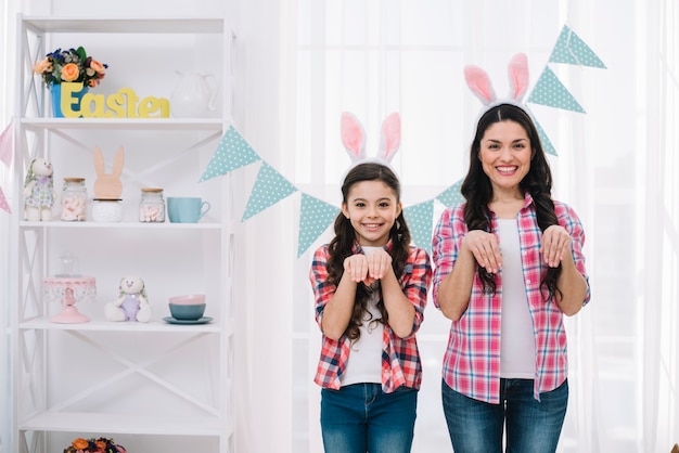 Retrato de madre e hija con orejas de conejo de Pascua posando como un conejo en casa