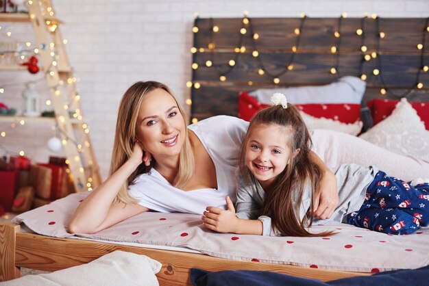 Retrato de madre e hija pasar la mañana de Navidad en la cama