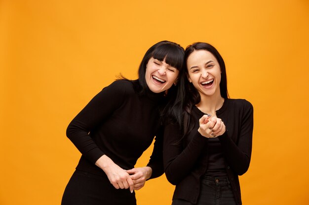 Retrato de una madre e hija sonriente feliz en amarillo