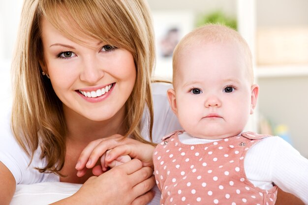 Retrato de madre sonriente con bebé recién nacido en casa