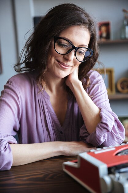 Retrato de una madura autora sonriente sentada en el escritorio