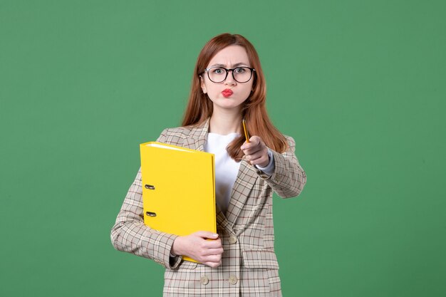 Retrato de maestra con archivos amarillos sobre verde