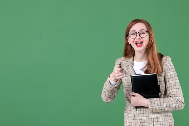 Retrato de maestra con bloc de notas riendo en verde