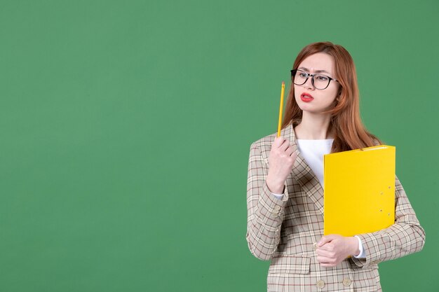 Retrato de maestra con documento amarillo y lápiz sobre verde