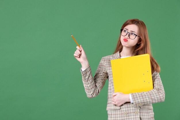 Retrato de maestra posando con lima amarilla y lápiz sobre verde