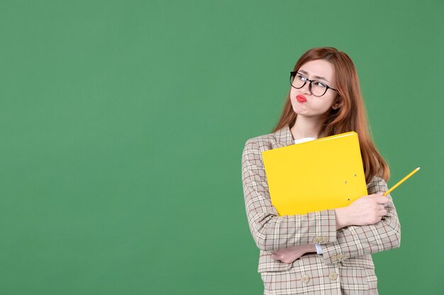 Retrato de maestra posando con lima amarilla y lápiz sobre verde