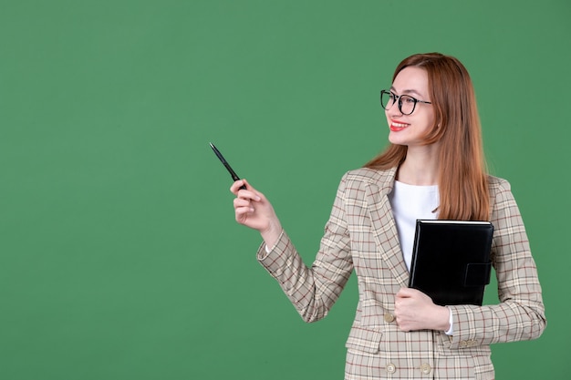 Retrato de maestra sosteniendo el bloc de notas en verde