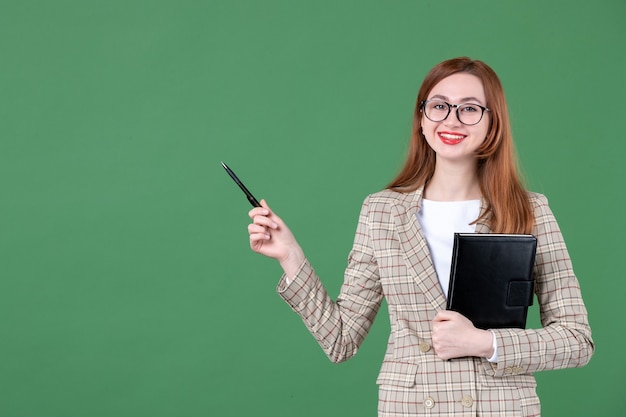 Retrato de maestra sosteniendo el bloc de notas en verde