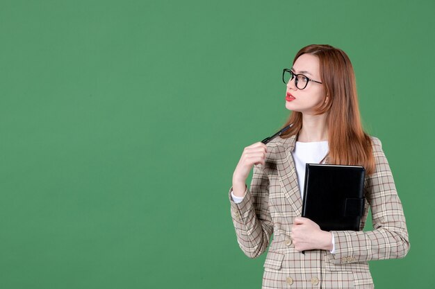 Retrato de maestra sosteniendo el bloc de notas en verde