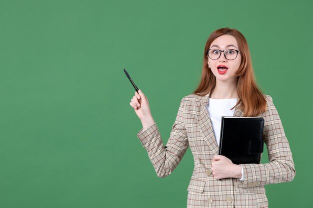 Retrato de maestra sosteniendo el bloc de notas en verde