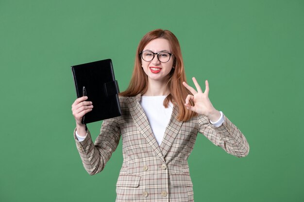 Retrato de maestra sosteniendo el bloc de notas en verde