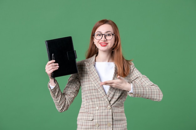 Retrato de maestra sosteniendo el bloc de notas en verde