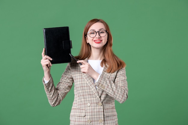 Retrato de maestra sosteniendo el bloc de notas en verde